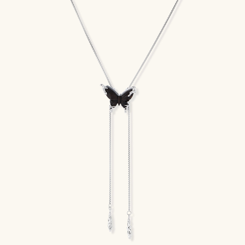 Wooden butterfly pendant necklace with cascading silver-toned chains on adjustable chain, available in amber and black.
